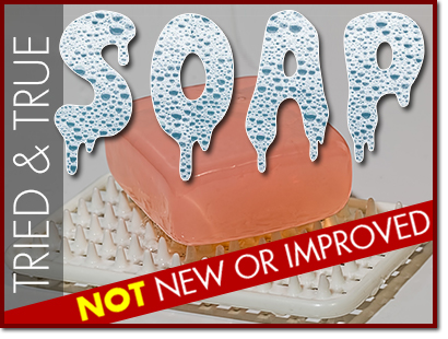 The word 'SOAP' in suds over a bar of soap on a mat along with the words 'Tried and True' vertically to the left in white over a grey bar and a diagonal red ribbon stating 'Not New or Improved' at the bottom.